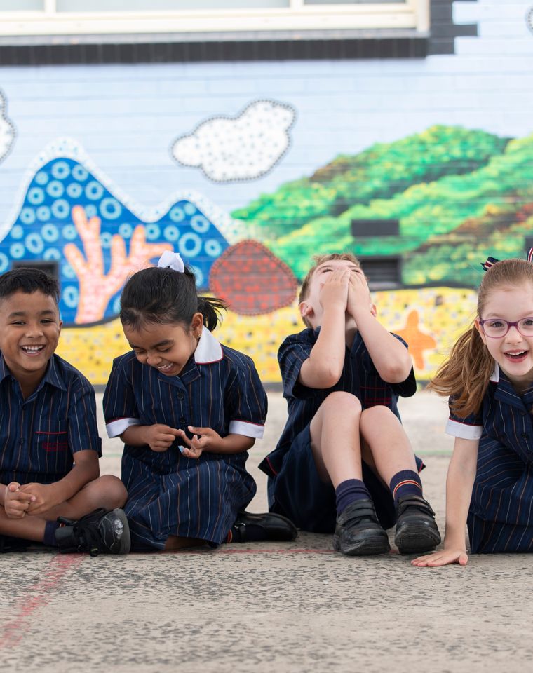 Four children laughing on the concrete