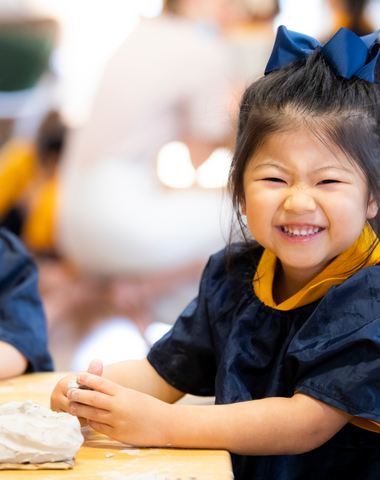 A kindergarten student playing with clay and smiling in the Early Learning Centre at Ruyton Girls' School