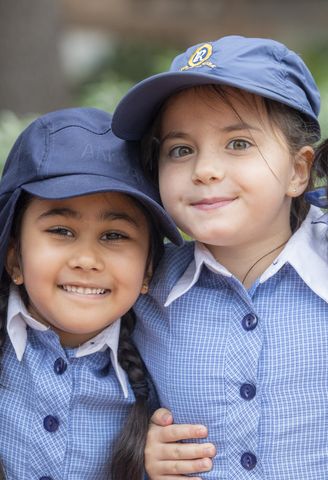 A group of Junior School students from Ruyton Girls' School smiling in the playground. They are wearing summer uniform.