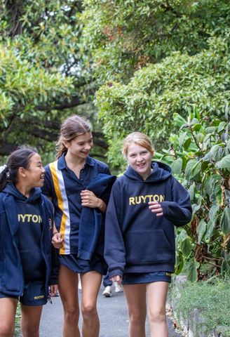 Senior School students smiling at each other as they walk down a garden path.
