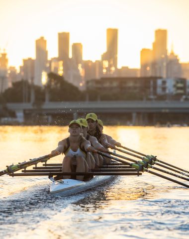 Ruyton students rowing on the Yarra River at sunrise with the Melbourne City skyline in the background.