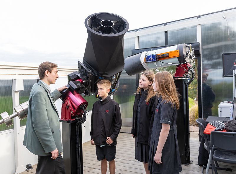 Four students stand in front of a telescope at the ELTHAM College Observatory.