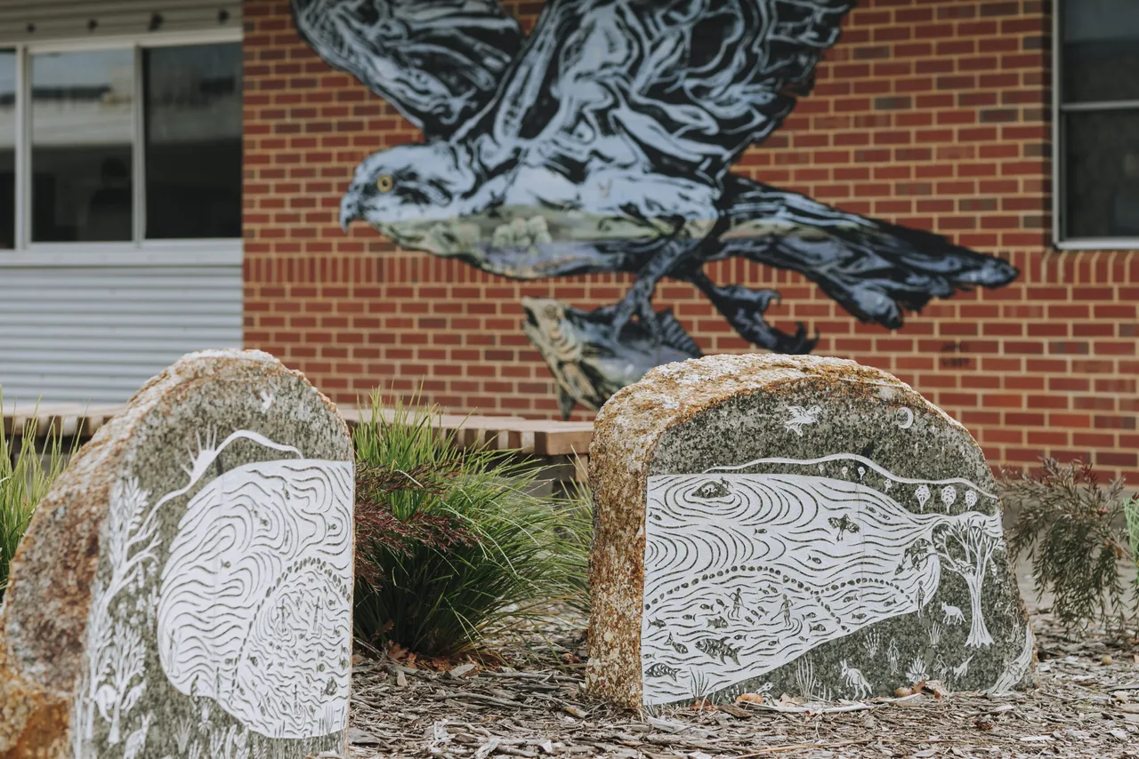 Wall with art in background, rocks with carved art in foreground