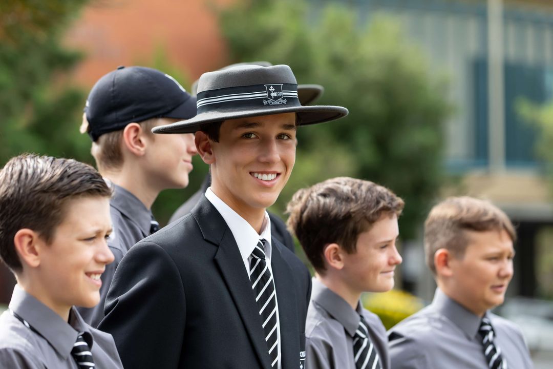 Group of mixed-age students standing in a line with one student smiling at camera