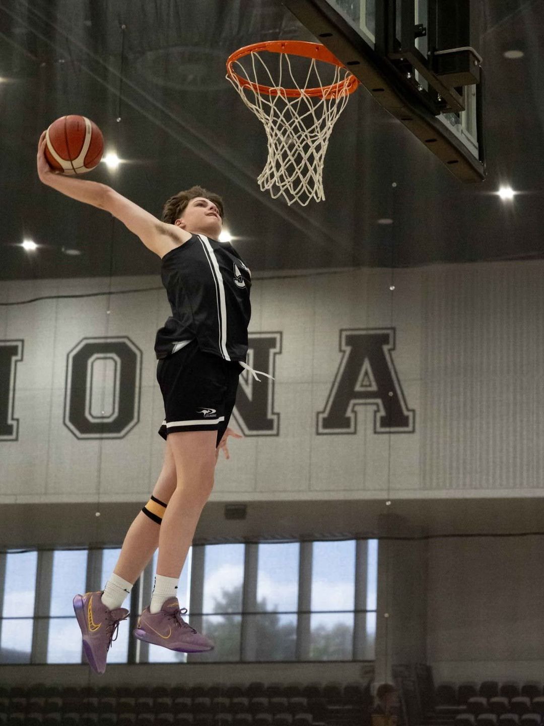A student soaring through the air about to dunk a basketball