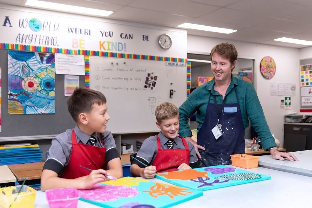 A teacher with two junior students doing artwork together
