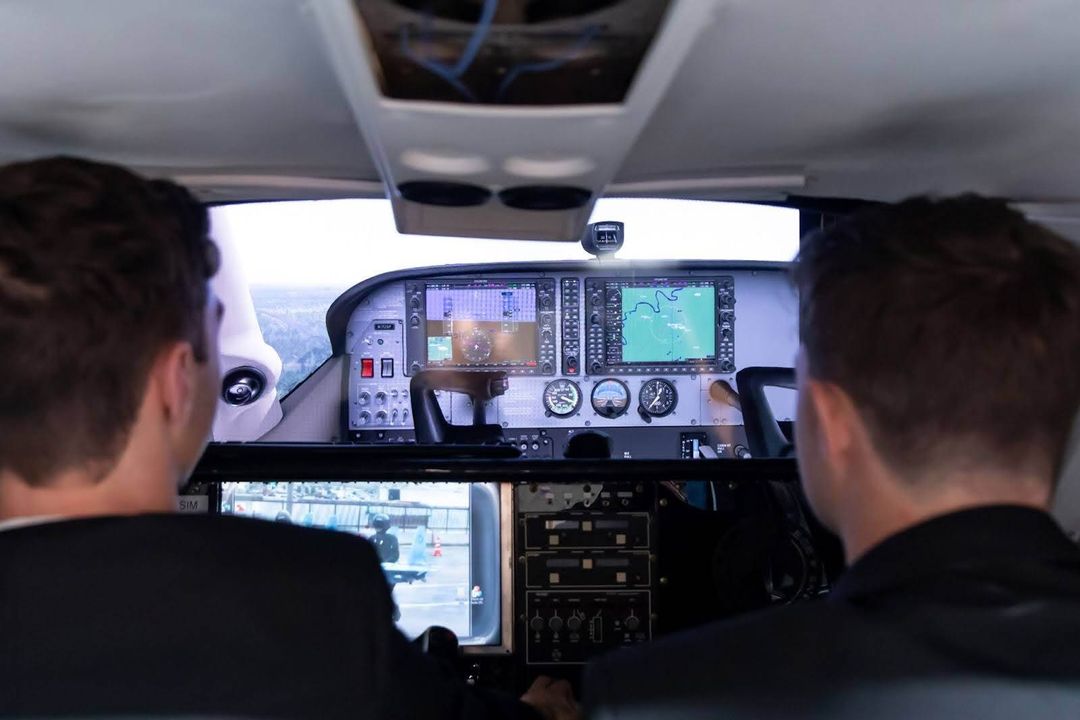 Two students sitting in a cockpit using virtual aviation technology