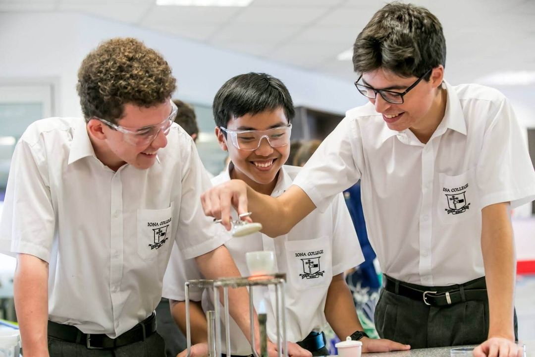 Three students with goggles on conducting and experiment over a bunsen burner