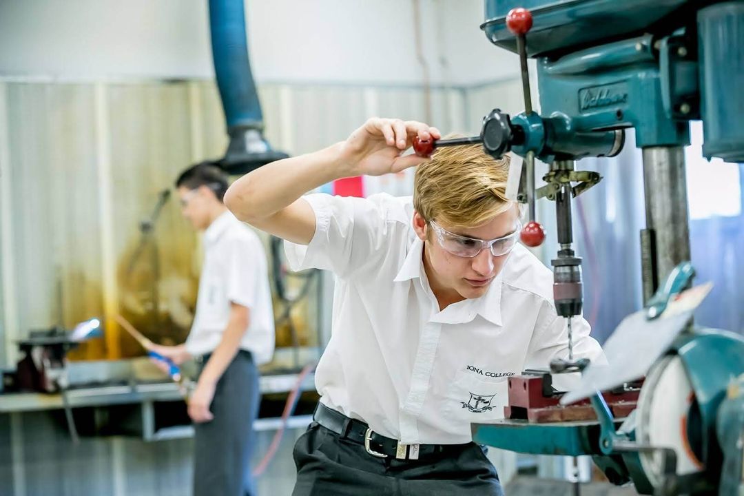 Student with safety googles uses a machine in the woodwork room