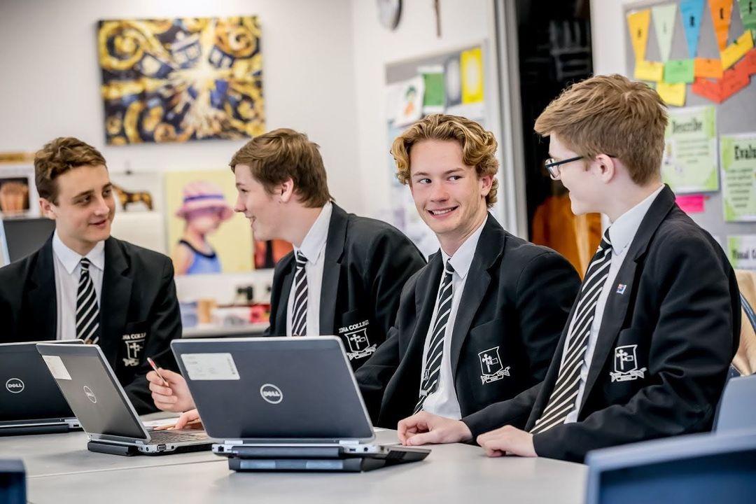 Four senior students chatting together wth laptops on the table