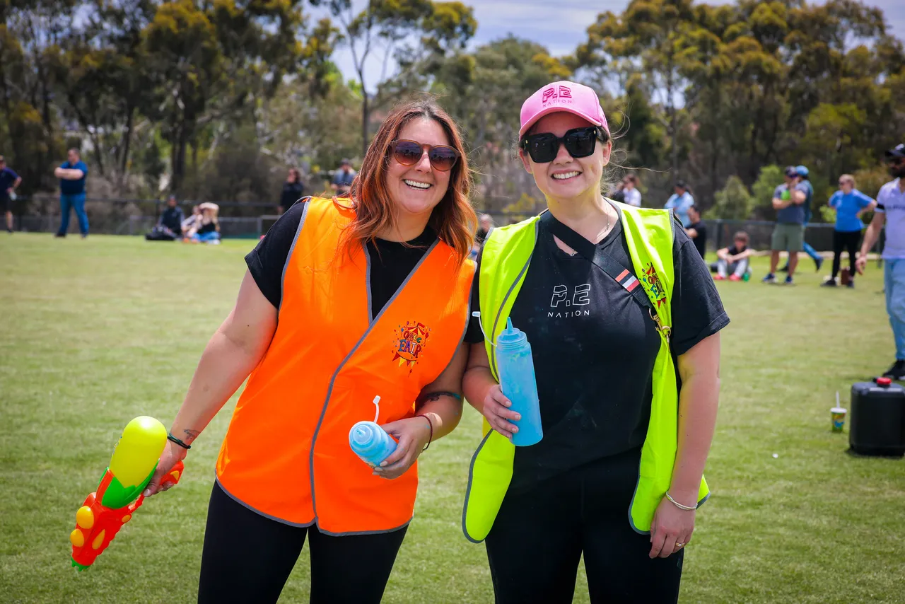 Overnewton Community Engagment Program parent volunteers smiling at camera as they support bi annual Parents and Friends Association fundraising Colour Fun Run held at Canowindra Campus Oval, Taylors Lakes.