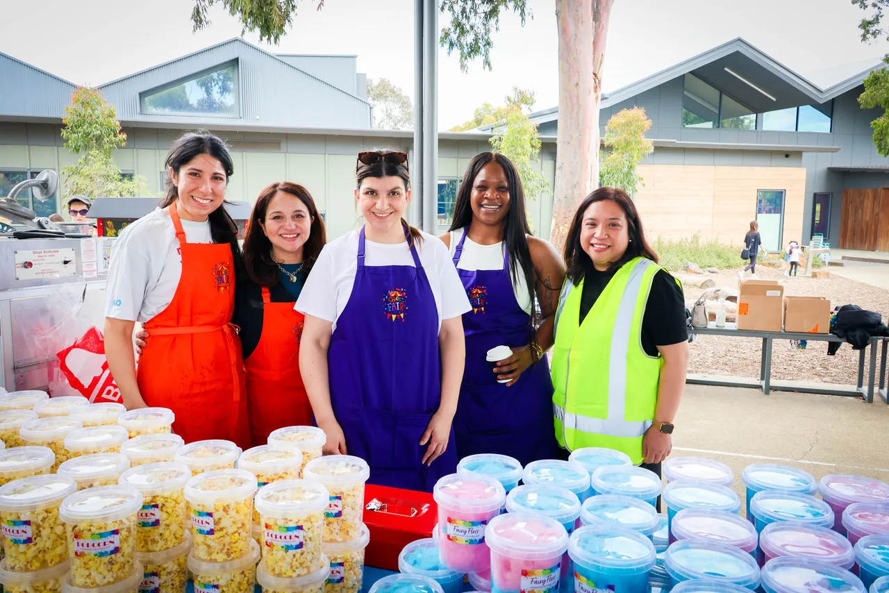Overnewton Community Engagment Program parent volunteers smiling at camera as they supports bi annual Parents and Friends Association fundraising Colour Fun Run held at Canowindra Campus, Taylors Lakes.