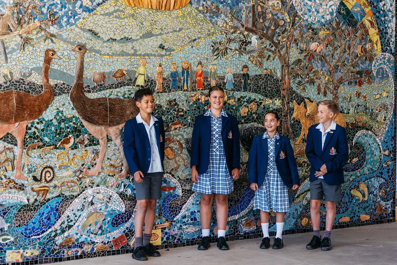 Upper primary school aged students outside the main entrance of the Middle School reception at Yirramboi Campus, standing in front of a beautiful Australian-inspired tiled mosaic.