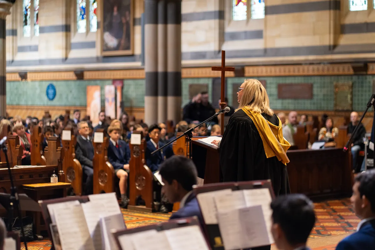 A photo taken from rear of stage showing the Principal of Overnewton Anglican Community College, an independent school in Melbourne, wearing academic robes, speaking at a lectern to the congregation of the College’s annual Founders’ Day Service at St Paul’s Cathedral.