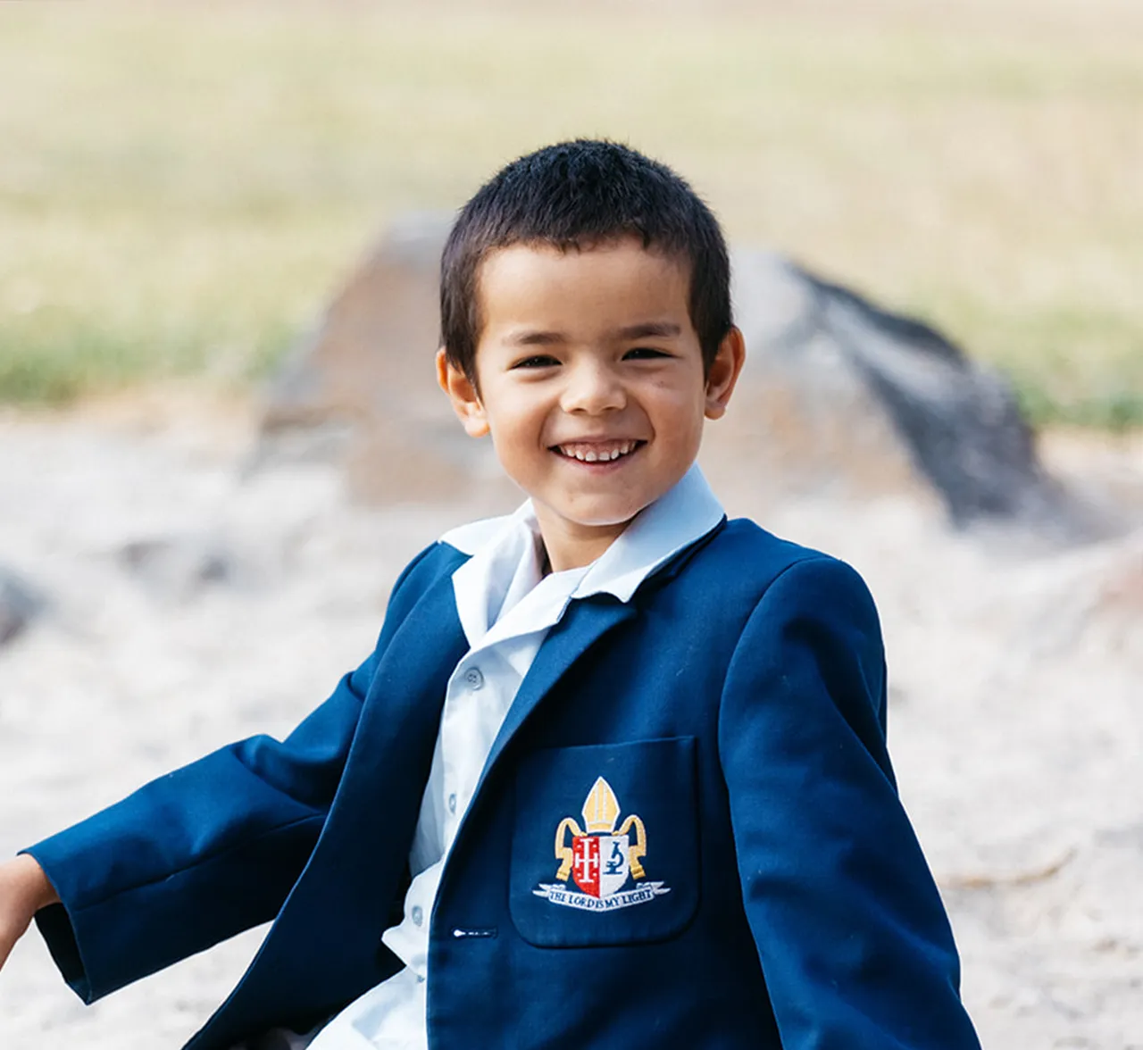 Primary school-aged boy playing in a sandpit looking to camera smiling