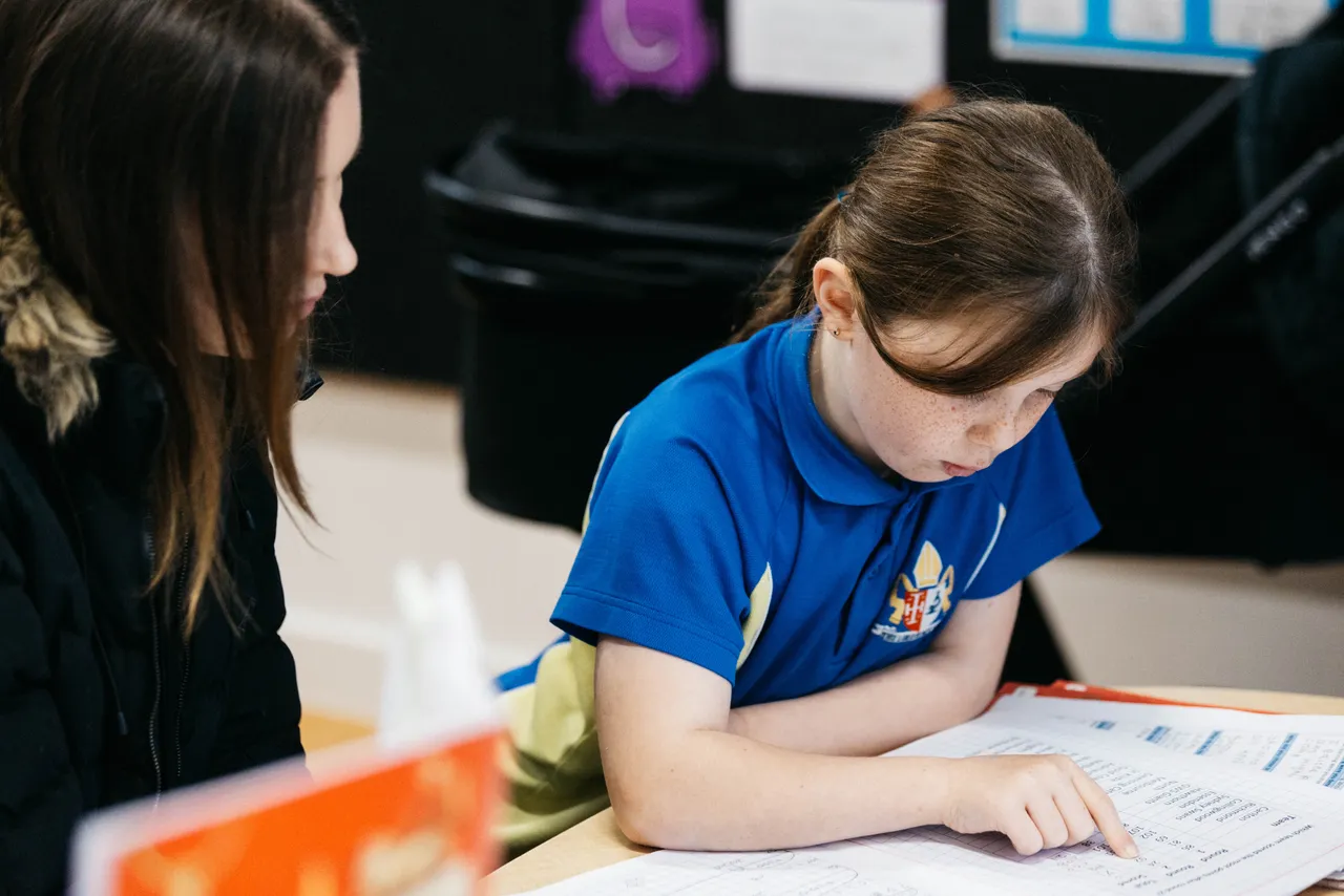 Lower primary school aged student proudly showing her school work to her mother, a guest at Overnewton's Junior School during their Celebration of Learning event.