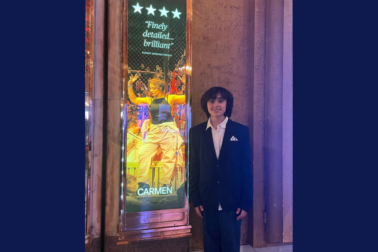Middle School Performing Arts student Miles standing beside the promotional poster for Opera Australia’s Melbourne season of Carmen, in which he is performing, at the Regent Theatre.