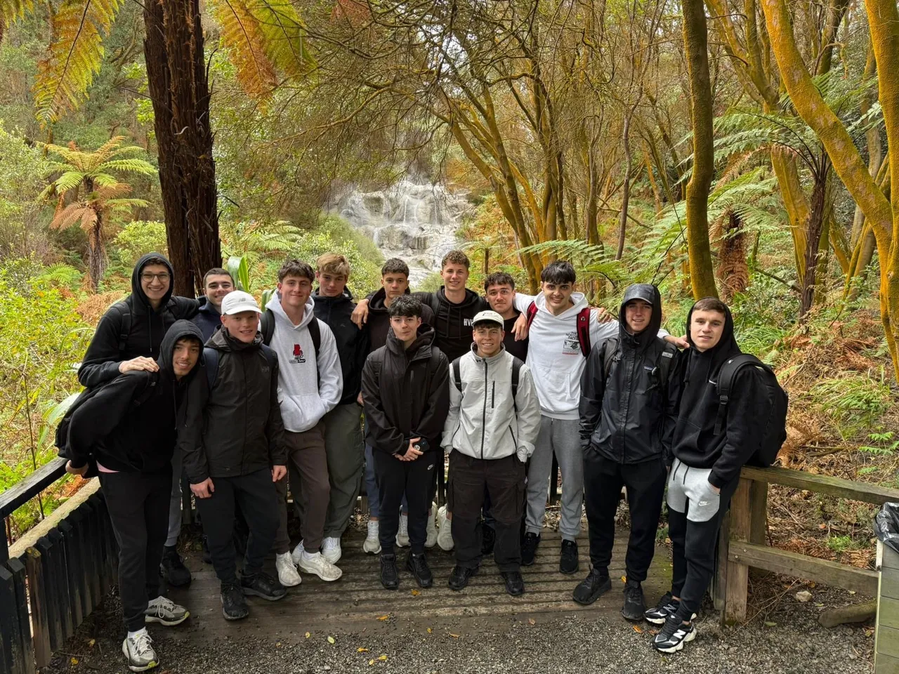 Overnewton upper secondary school-aged students standing in front lush rainforest laden with the iconic New Zealand fern, during the annual Year 11 Co Curricular educational travel program.