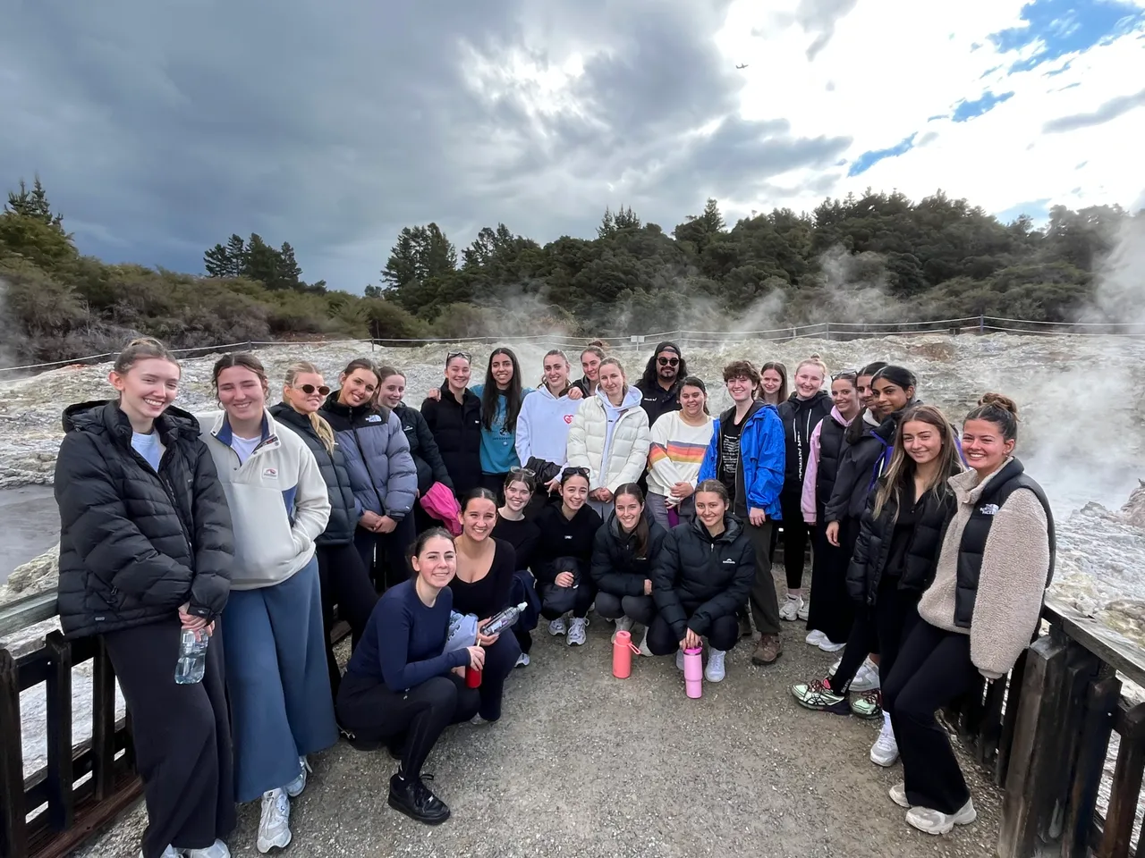 Overnewton upper secondary school-aged students standing in front of a steaming geothermal spring in Rotorua, New Zealand, during the annual Year 11 Co Curricular educational travel program.