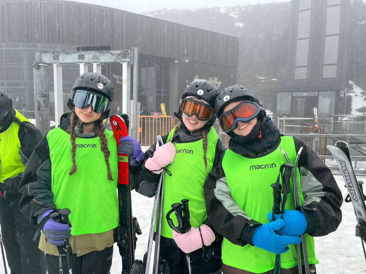 Upper secondary school aged students wearing ski gear and goggles, holding skis and stocks, on a foggy ski field in Queenstown, New Zealand, during a Year 11 Co Curricular educational travel program.
