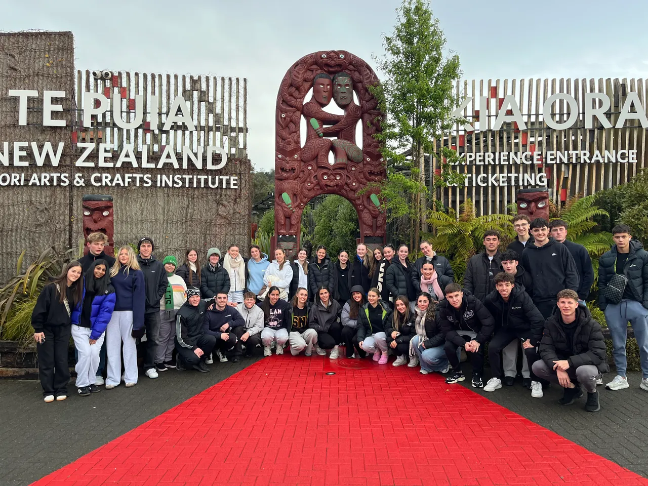 Overnewton upper secondary school aged students and staff, standing in front of large tourist sign in New Zealand during a Year 11 Co Curricular educational travel program.