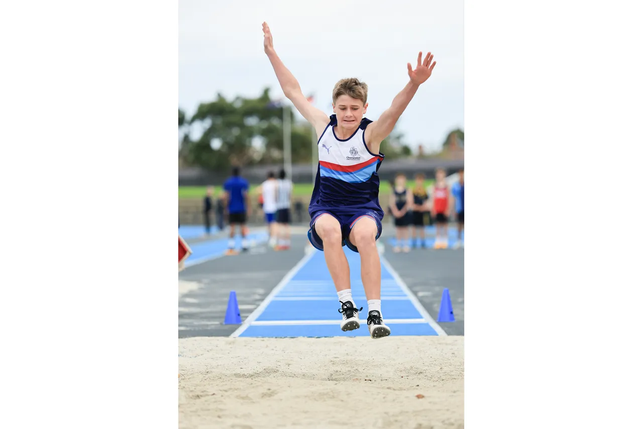 Action shot of upper secondary school aged student competing in the long jump event at the 2026 ACS Athletics Championship.