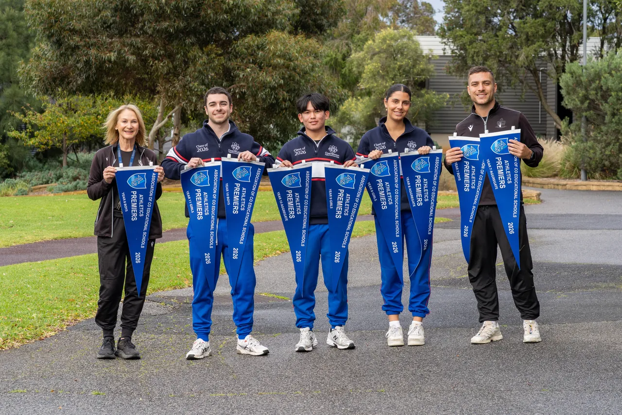Three upper secondary school aged students and two staff members proudly holding a record-beating nine premiership flags won by Overnewton at the 2026 ACS Athletics Competition.
