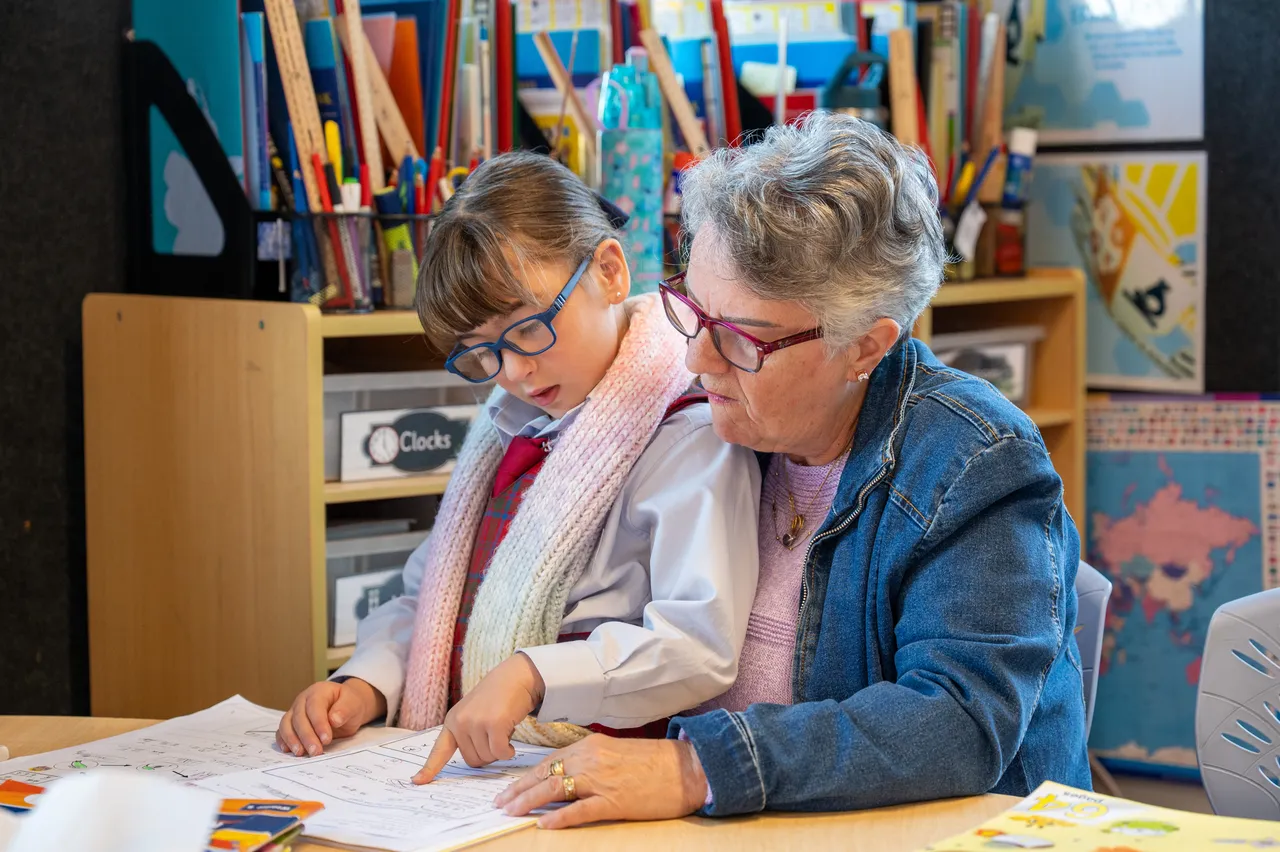 Lower primary school aged student proudly sharing her work with grandmother during the Junior School Celebration of Learning event.