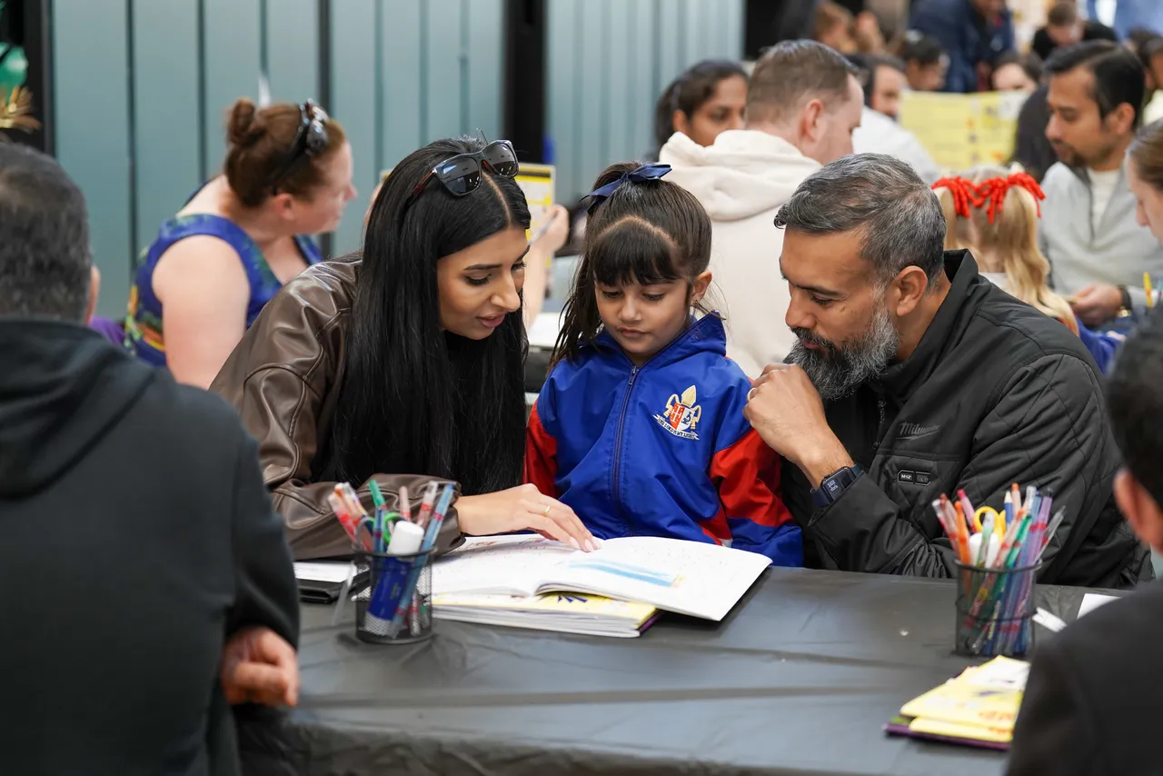 Lower primary school aged student showing her parents her school work during the Junior School 2026 Celebration of Learning event.