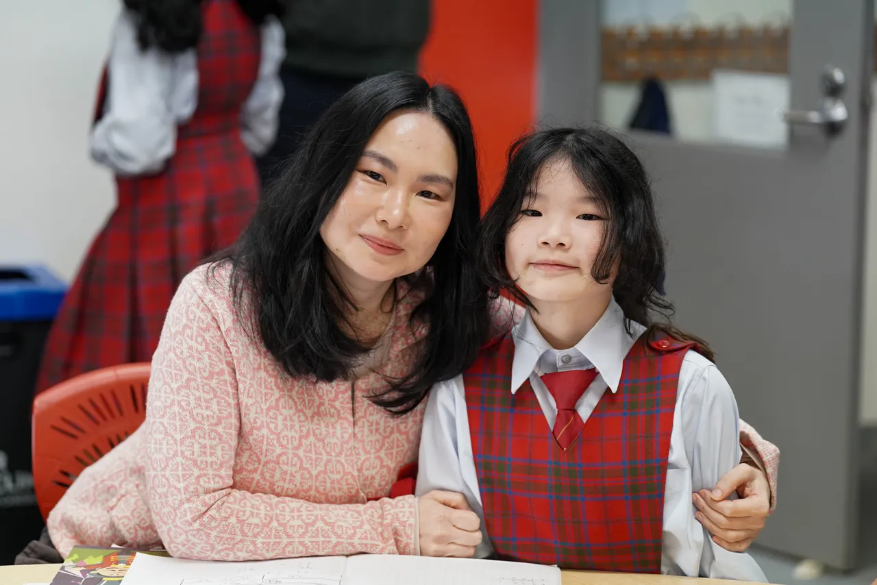 Middle primary school aged student proudly posing with her mother in her classroom during the Junior School's 2026 Celebration of Learning event.