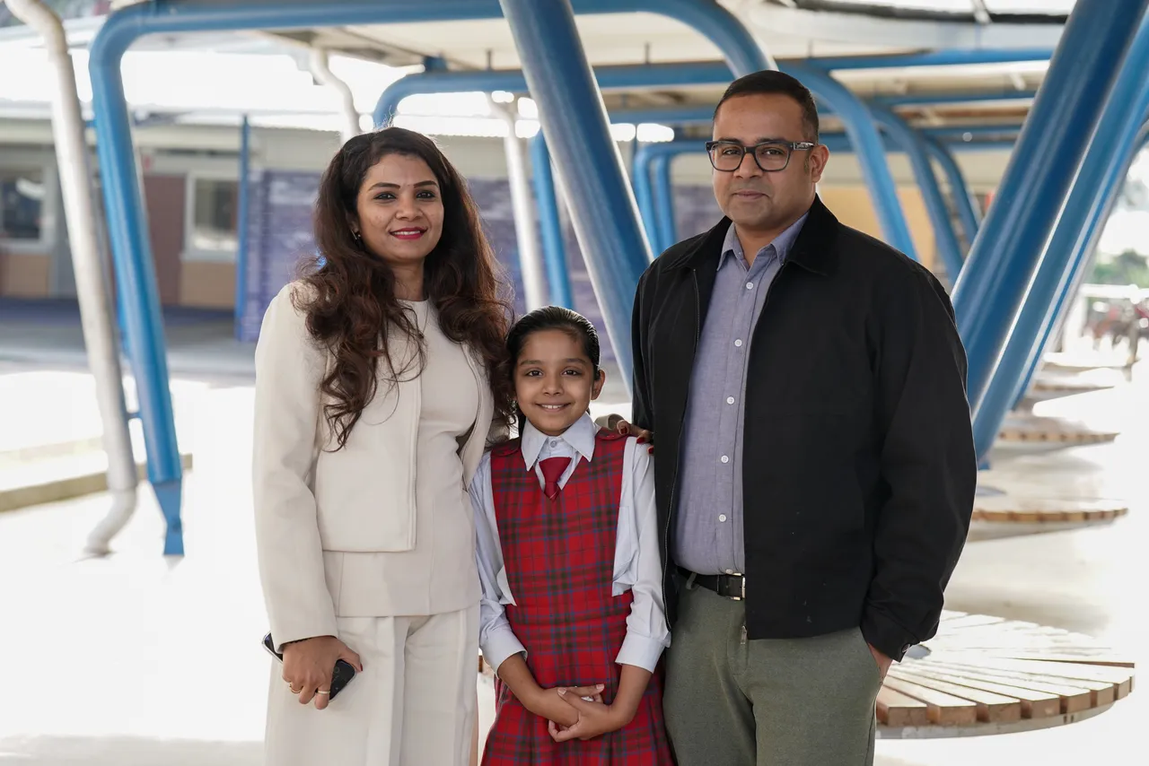 Middle primary school aged student, smiling with her parents who are guests at Overnewton's Junior School during the 2026 Celebration of Learning event.