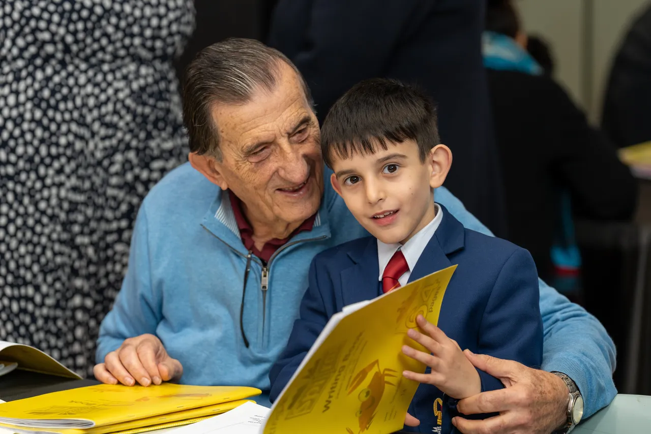 Lower primary school aged student proudly sharing his work with his grandfather during the Junior School 2026 Celebration of Learning event.