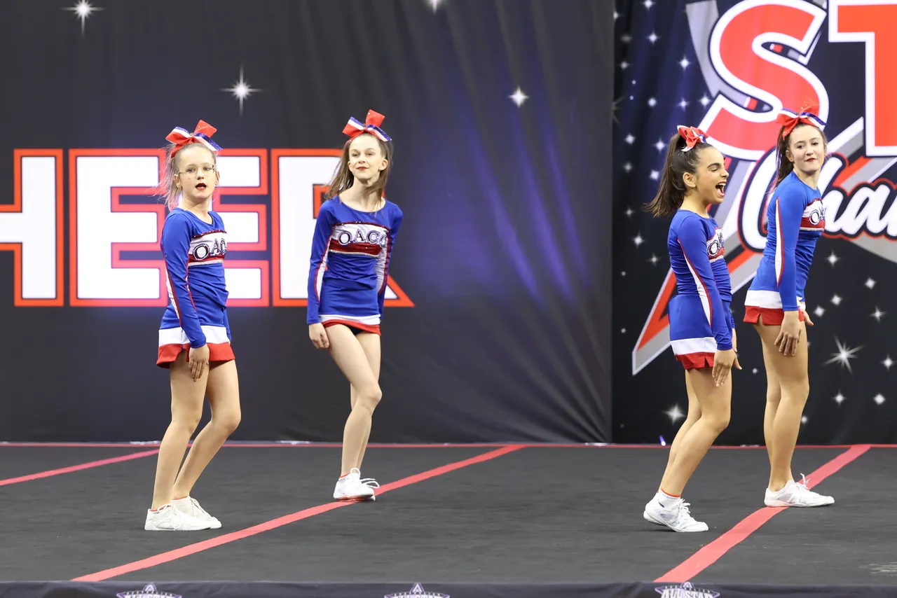 Lower secondary school aged students from an Overnewton Cheer team performing a prize-winning routine on stage at the 2025 AASCF State Championships.