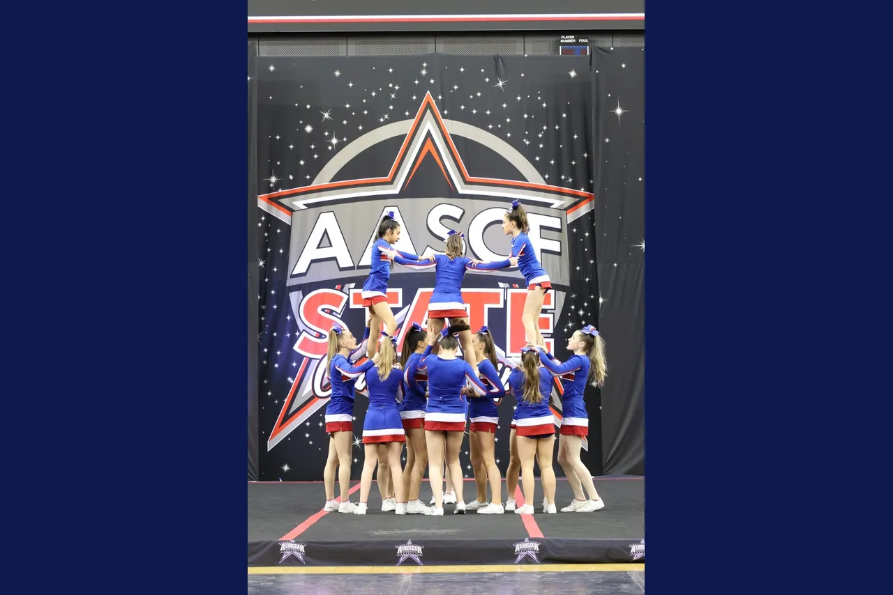 Lower secondary school aged students from Overnewton's Middle School Cheer team performing a technical acrobatic formation as part of their prize-winning routine on stage at the 2025 AASCF State Championships.