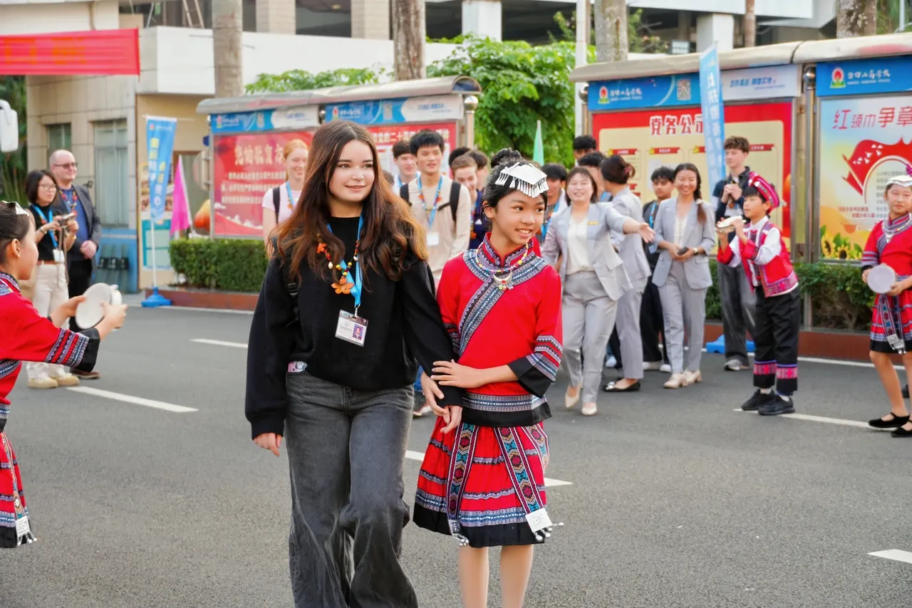 Middle secondary school aged student being escorted by a Chinese student in traditional dress, at the commencement an international school visit in Hainan as part of Overnewton's 2025 educational travel tour of China.