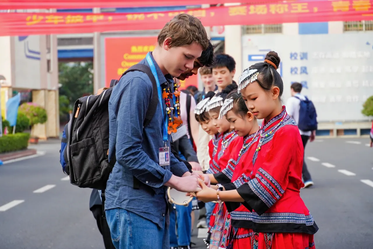 Upper secondary school aged students holding hands with students in traditional dress during a welcome ceremony at an international school visited on Overnewton’s 2025 China tour.