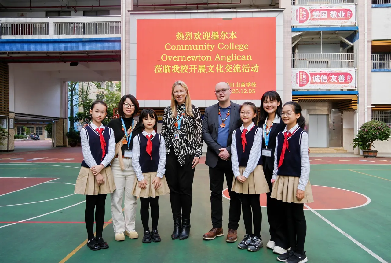 Overnewton staff and local school students standing in front of a welcome sign at an international school in Hainan during Overnewton’s 2025 China tour.