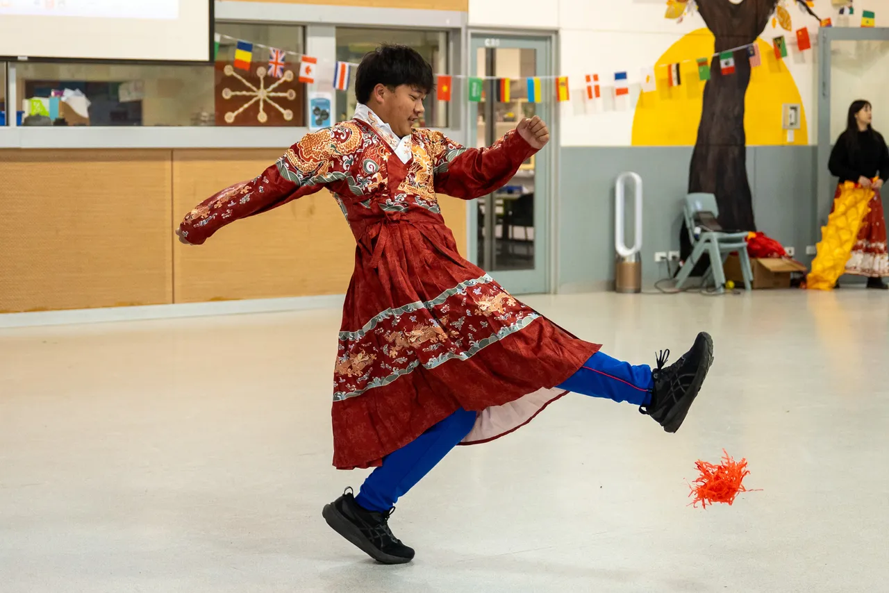 A middle secondary school-aged student from Year 9 wearing traditional Chinese dress and playing a game of feathered hacky sack as part of a lunchtime activity during Overnewton’s 2025 Languages and Culture Week.