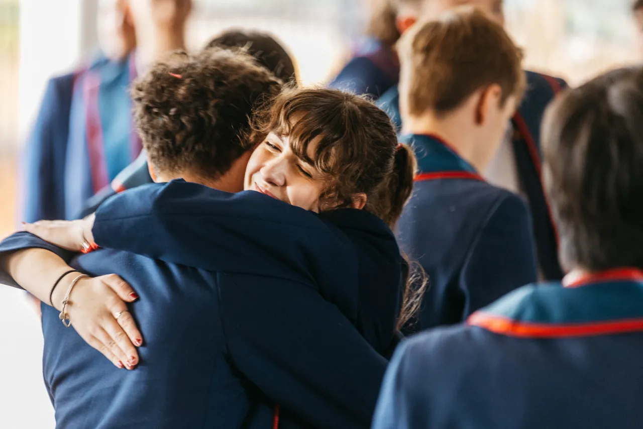 Two upper secondary school aged students from Overnewton’s Class of 2024 sharing a congratulatory hug after their Final Assembly.
