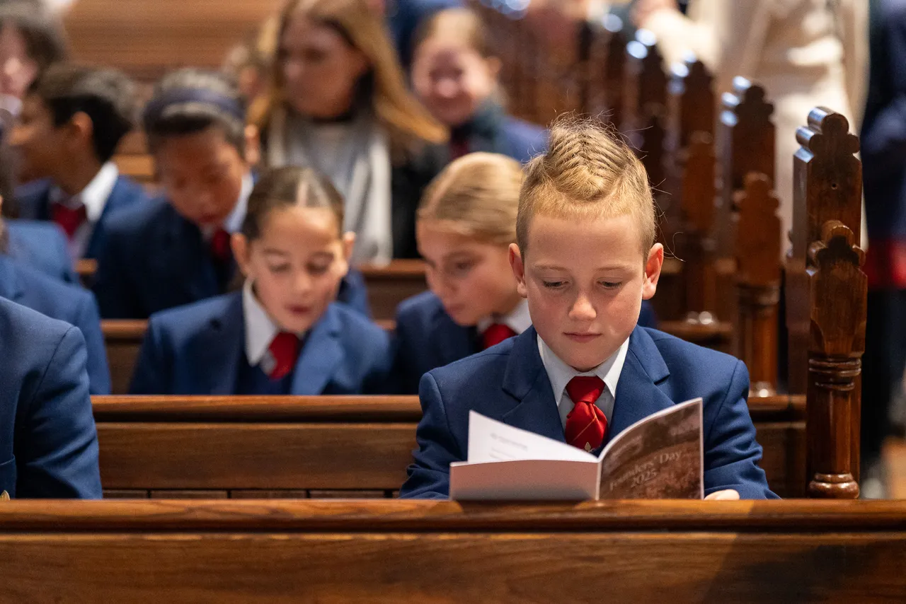 Upper primary school aged student from Overnewton Anglican Community College, seated in a pew at St Paul’s Cathedral during the College Founders’ Day service, holding and reading the official service booklet.