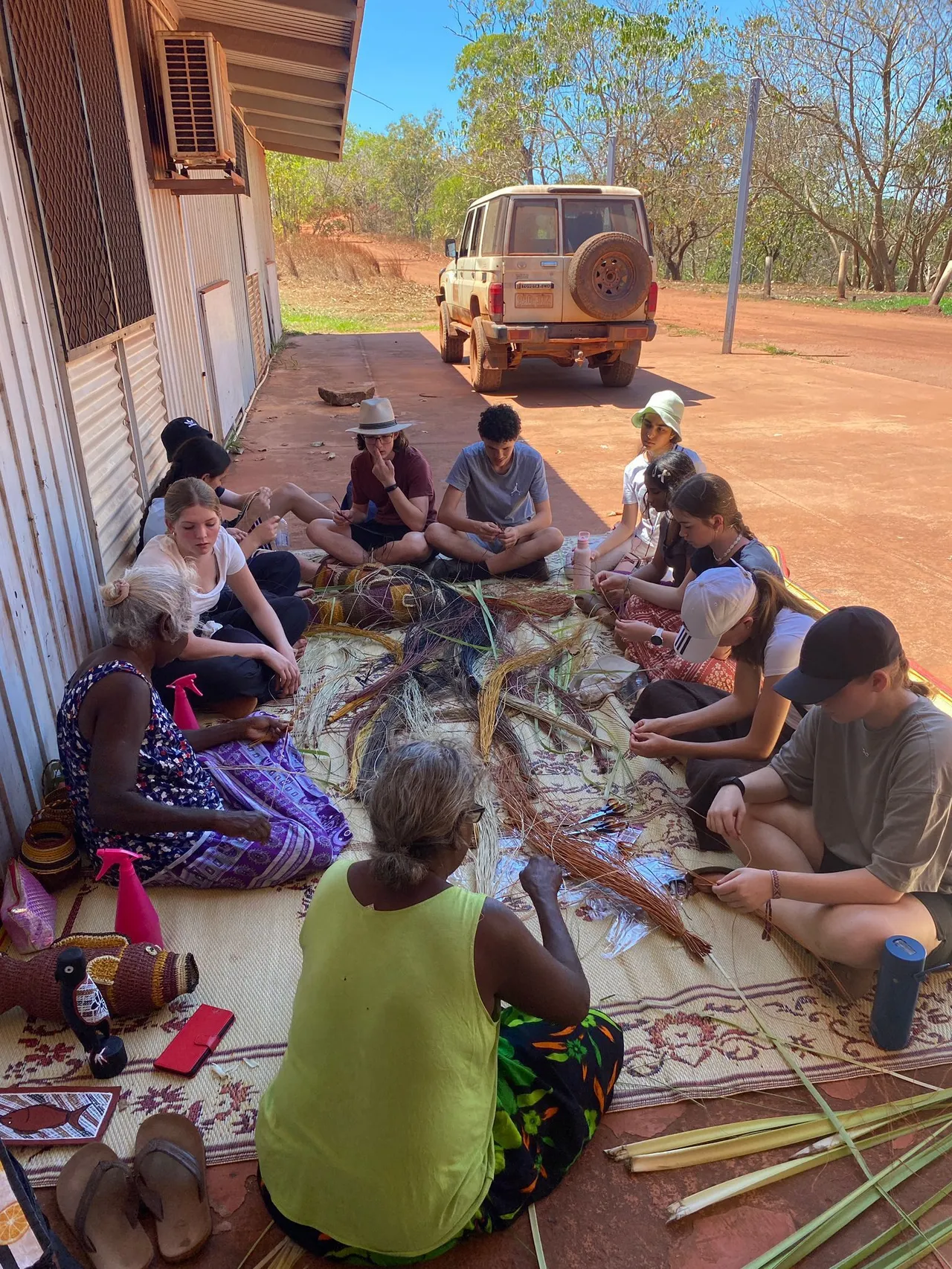 A group of upper secondary school-aged students participating in a traditional grass weaving craft workshop with Indigenous elders at Elcho Island in the Northern Territory during Overnewton’s 2025 Galiwin’ku educational travel program.