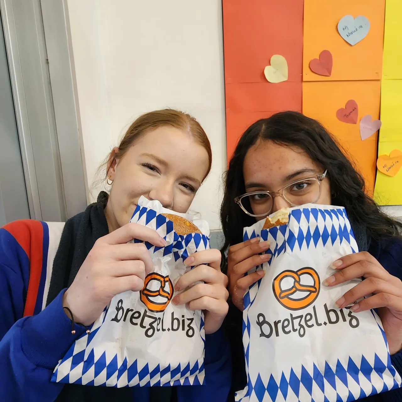 Two middle secondary school-aged students from Year 9 holding German pretzels in traditional paper bags during Overnewton’s 2025 Languages and Culture Week.