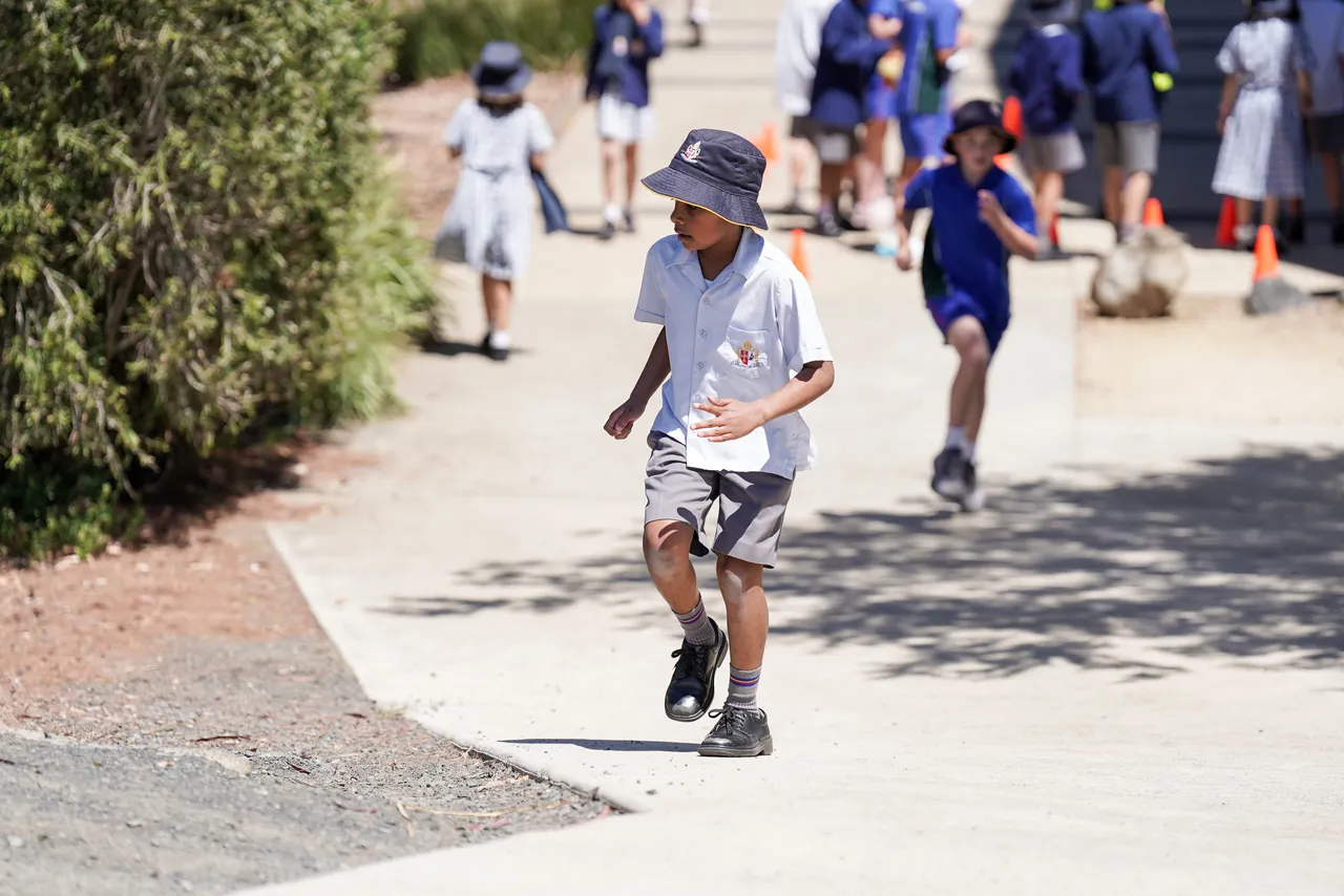 Middle primary school aged student from Overnewton Junior School running up a path at Canowindra Campus, searching for a hidden miniature duck during House Activate Day.