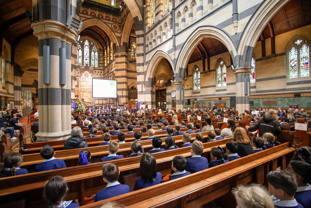 Rear view of full pews of primary school aged students from Overnewton Junior School gathered at St Paul’s Cathedral for the annual Junior School Carol Service.