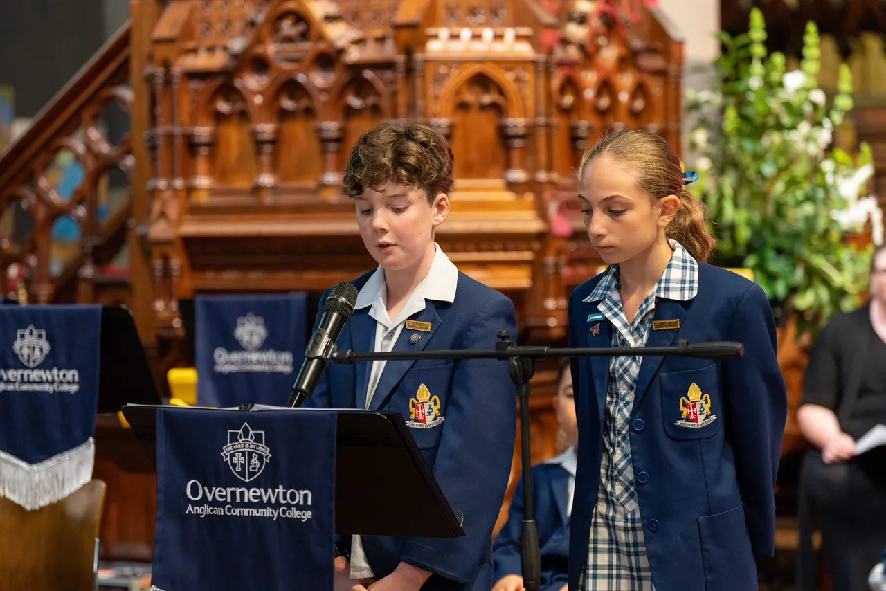 Junior School student leaders speaking at a lectern as part of Overnewton's annual Junior School Carol Service, held at St Paul's Cathedral.