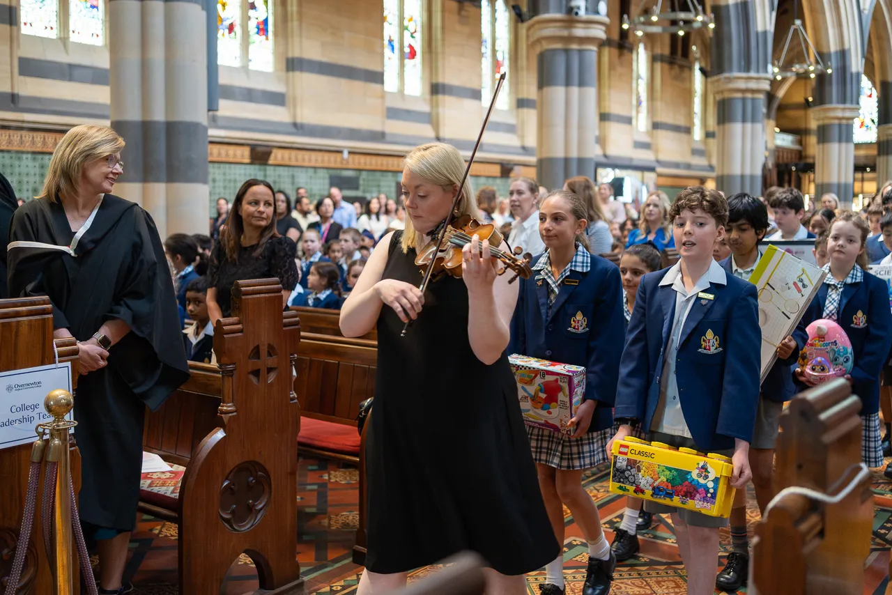 Violin teacher, Prue Jury, leads a procession of Student Representative Council members to the front of St Paul's Cathedral, where they will lay donated toys as part of the much-loved annual Junior School Carol Service.