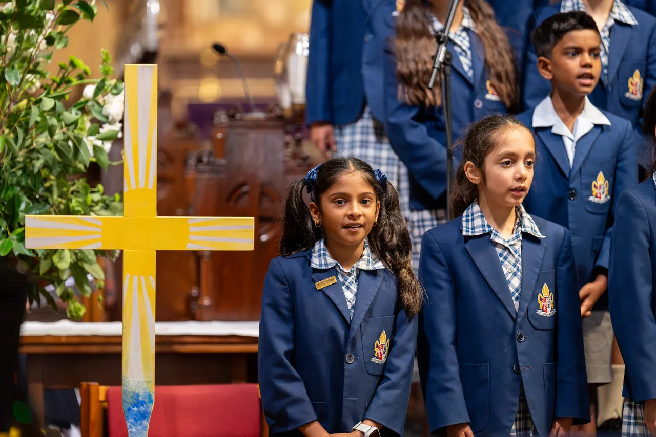 Junior School students singing on choir risers with a student-designed cross in the foreground at St Paul’s Cathedral during Overnewton's annual Junior School Carol Service.