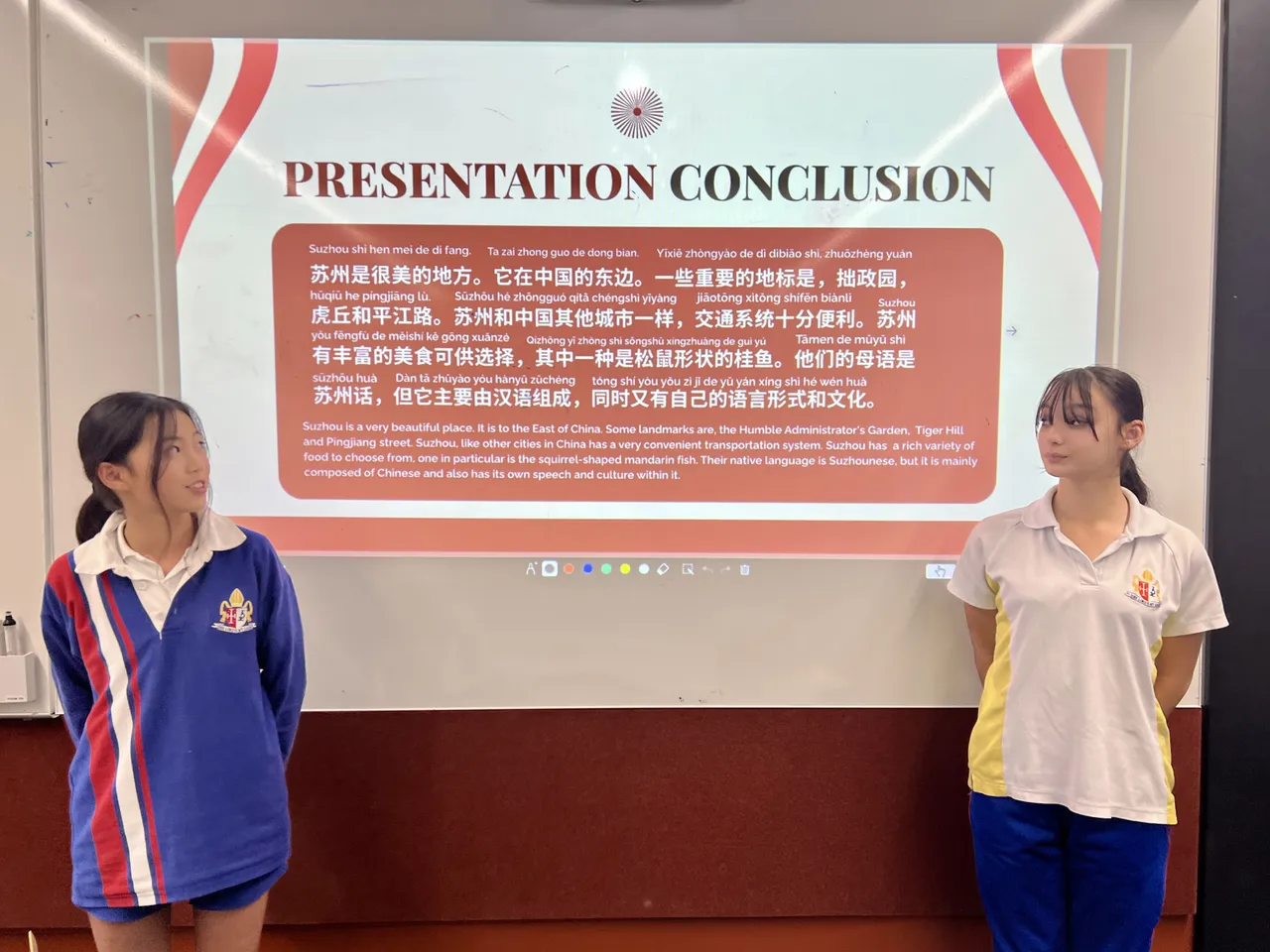 Two middle secondary school-students standing beside a Chinese language presentation during Overnewton's 2025 Languages and Culture Week.