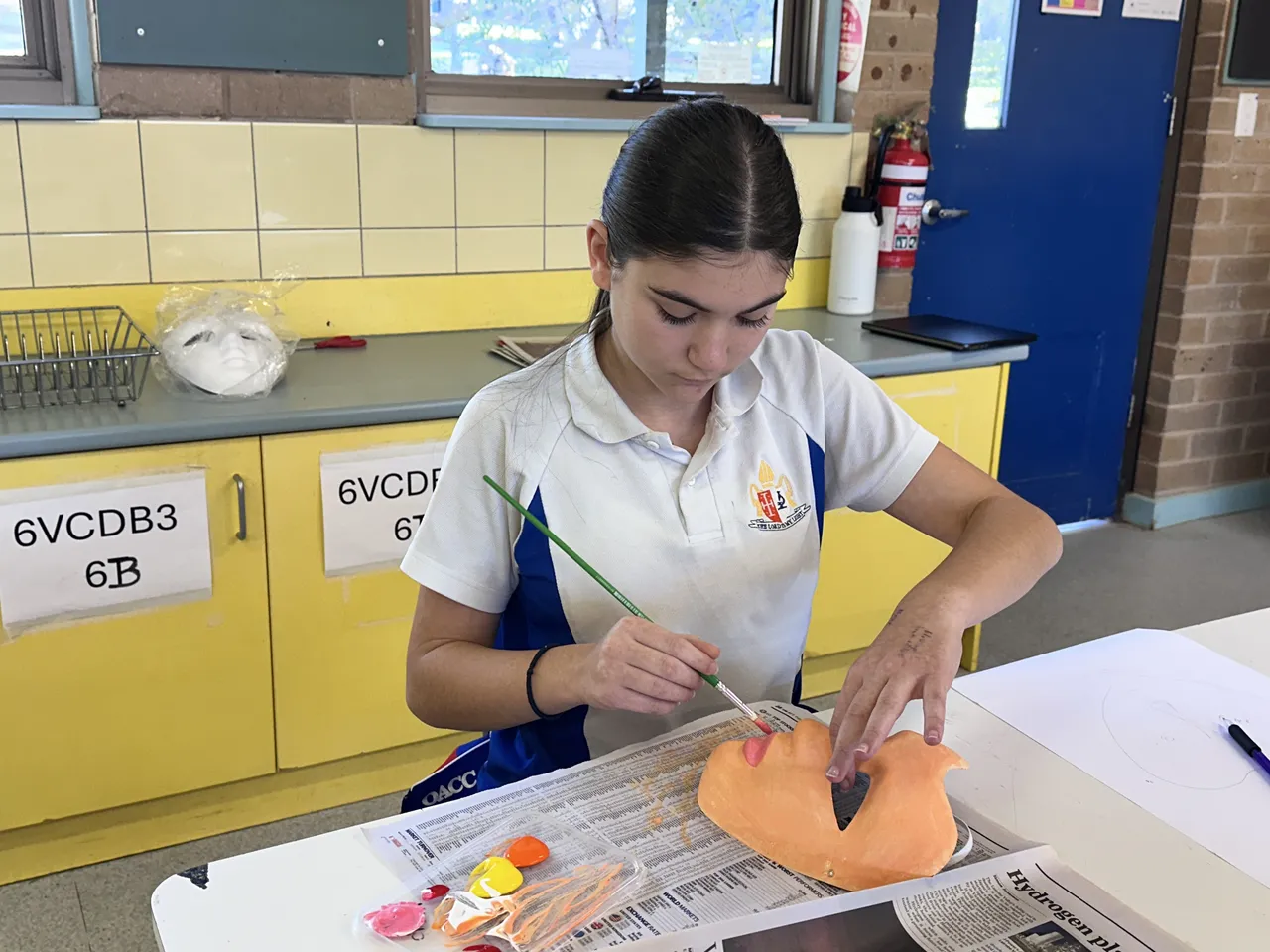 Secondary school-aged student from Middle School painting a mask during Overnewton’s 2025 Languages and Culture Week.