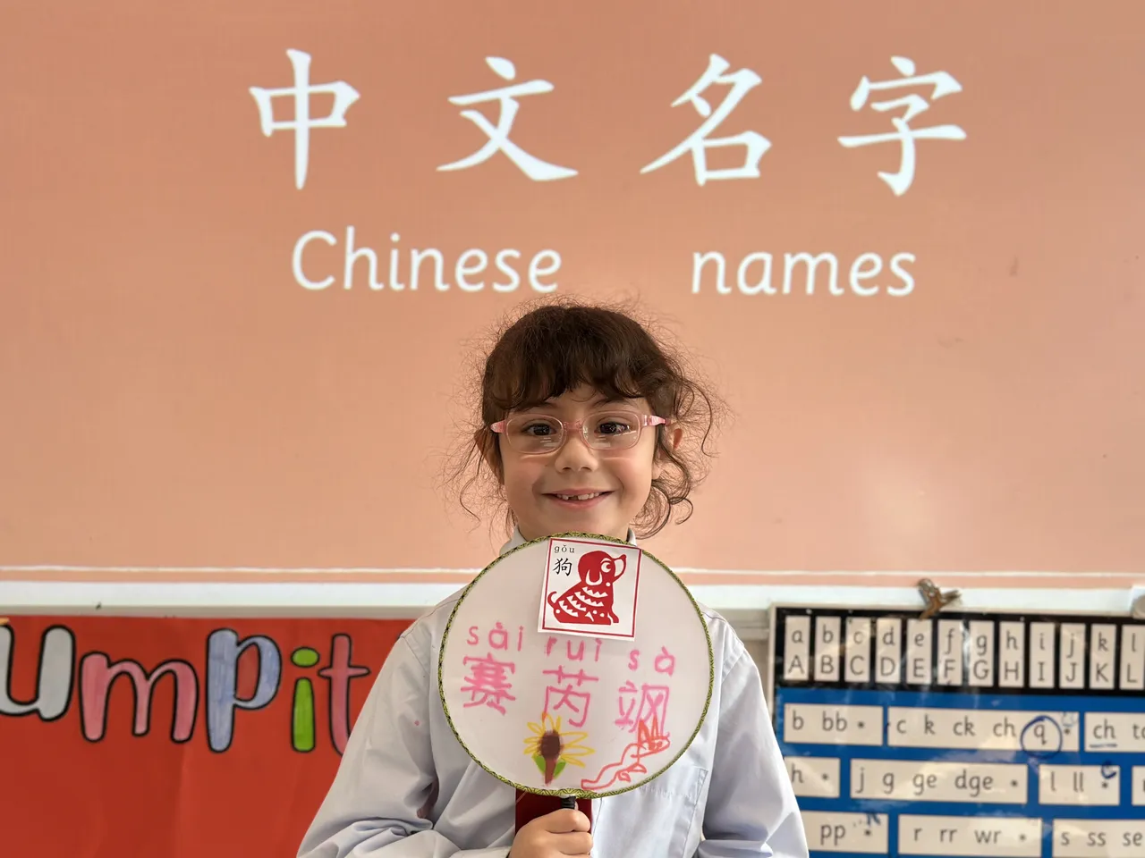 A lower primary school-aged student from the Junior School proudly holding a traditional Chinese fan that she decorated with the characters that spell her name, during Overnewton's 2025 Languages and Culture Week celebrations.